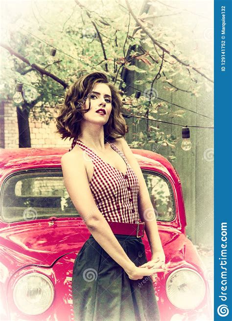 pretty pin up girl posing on a red retro car background playful gaze fixed on camera stock