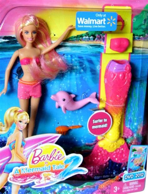 barbie doll in pink swimsuit with dolphin and dolphin toy on the beach next to it
