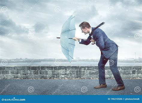 Businessman With An Umbrella Is Facing Strong Headwind Stock Photo