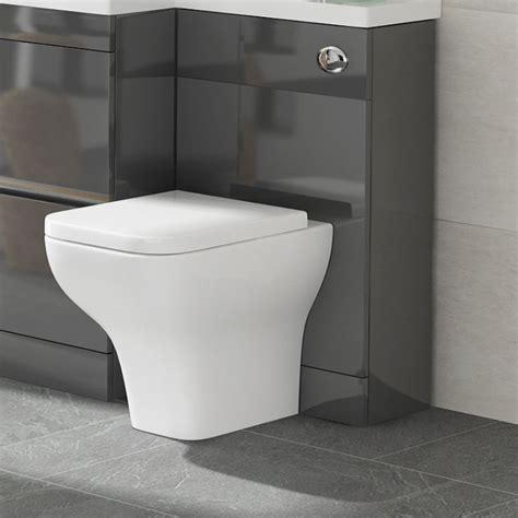 A White Toilet Sitting In A Bathroom Next To A Wall Mounted Faucet And Sink