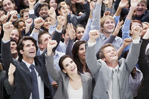 Smiling Crowd Of Business People Cheering With Arms Raised Stock Photo