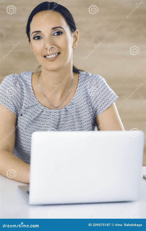 cheerful smiling businesswoman working with laptop computer while sitting at the desk in modern