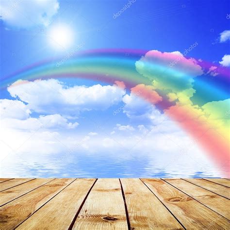 Blue Sky Background With Rainbow And Reflection In Water
