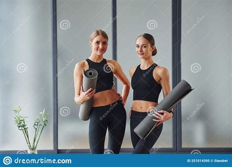 Standing With Mats In Hands Two Women In Sportive Wear And With Slim Bodies Have Fitness Yoga