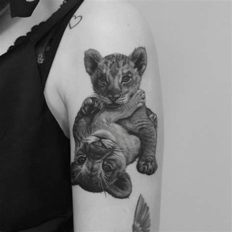 Black And Grey Lion Cubs Tattoo On The Upper Arm