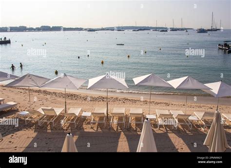 Rows Of White Umbrellas And Sun Loungers Line The Golden Sandy Beach In