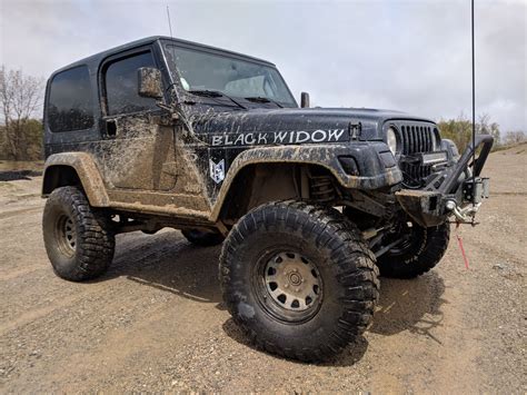 A Black Widow Jeep Is Parked In The Dirt
