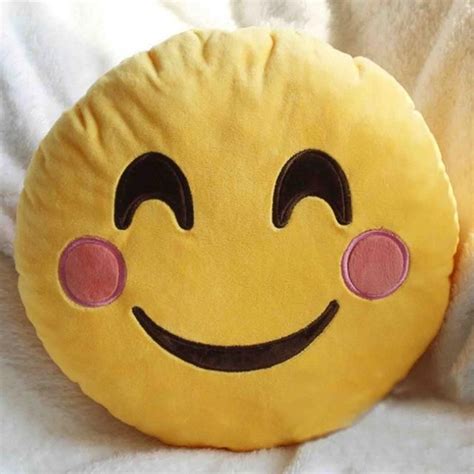 A Yellow Smiley Face Pillow Sitting On Top Of A White Bed Sheet With Pink Eyes