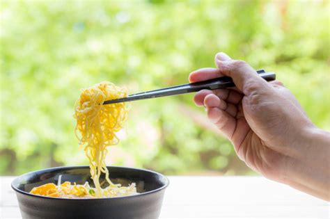 These noodle/rice bowls with chopsticks are great for noodle soup or a rice bowl. Chinese egg noodles with hand hold chopsticks on wood table | Premium Photo