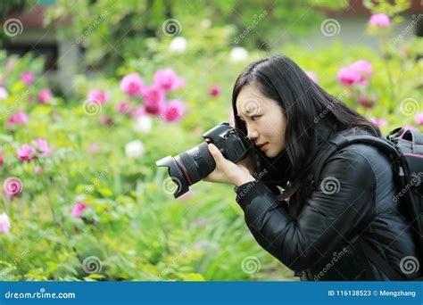 close up aisan chinese woman photographer hold camera close to her face work in nature against