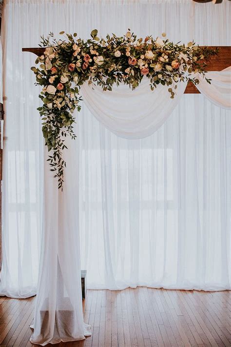 Wood Wedding Ceremony Arbor With White Draping And Romantic Florals In