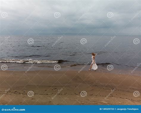 Aerial Beautiful Young Blonde Woman Beach Nymph In White Dress Near Sea With Waves During A Dull