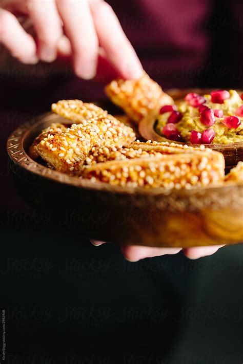 Woman With Dish Of Cheese Bites With Houmous Dip And Pomegranate By