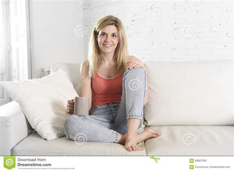 Young Attractive Woman Holding Cup Of Coffee Sitting On Sofa Couch At
