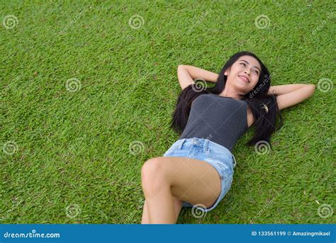 Glückliche Junge Schöne Asiatin Die Auf Gras Am Park Niederlegt Stockbild Bild Von Unten