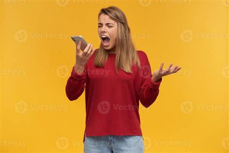 mad disappointed girl keeps mobile phone in her hand looking on it like making a call opened