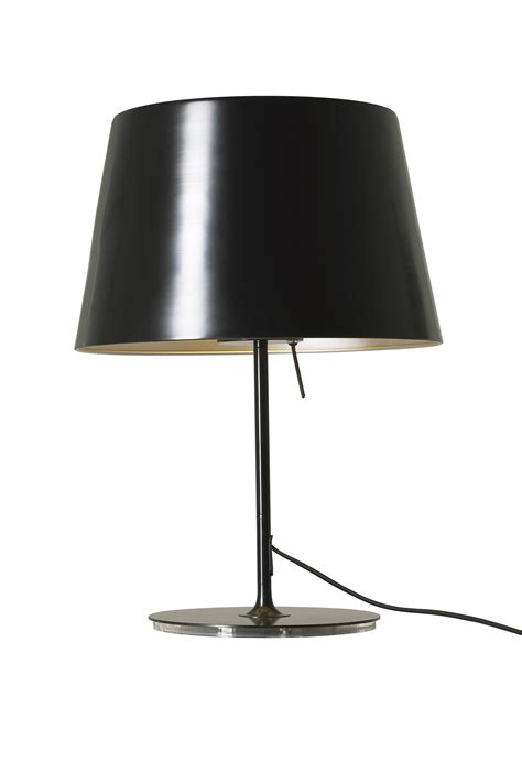 A Black Lamp On A Metal Base With A White Light In The Corner Behind It
