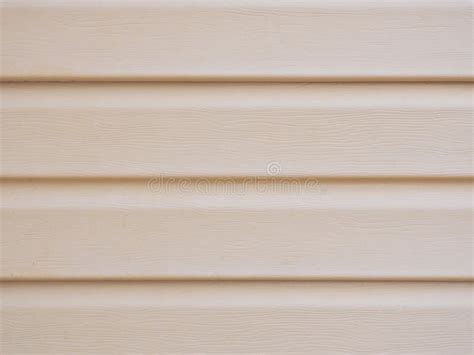 A Wall Of A House Sheathed With Plastic Siding Close Up Light Beige