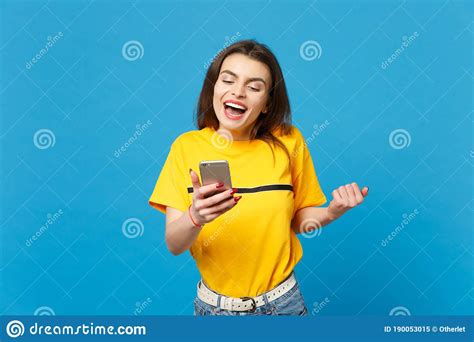 Funny Young Woman In Vivid Casual Clothes Doing Winner Gesture Using Mobile Phone Typing Sms