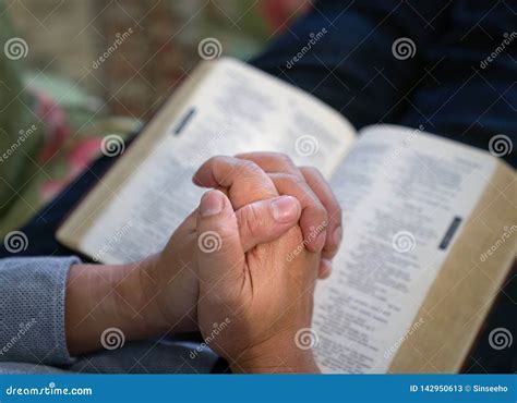 Praying Male Hands Clasped Together On An Open Bible Stock Image