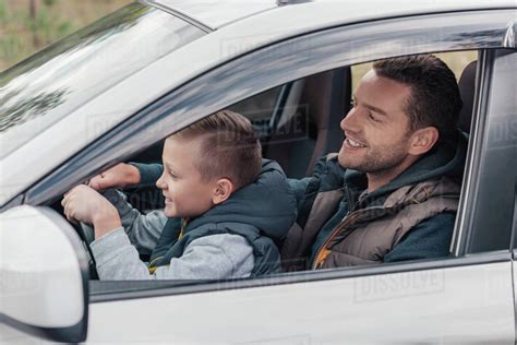 Side View Of Happy Father And Son Driving Car Together Stock Photo