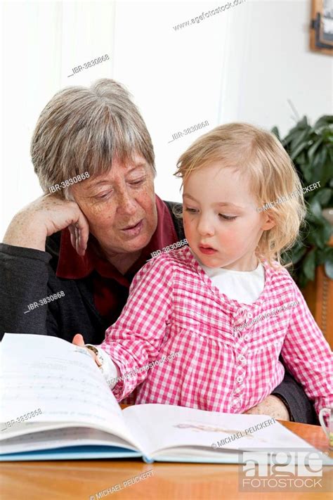 Grandmother Reading From A Book To Her Granddaughter 3 Years Stock