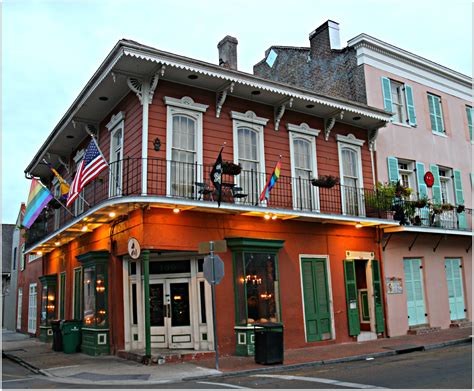 An Orange Building With Green Shutters And American Flags On The Balconies