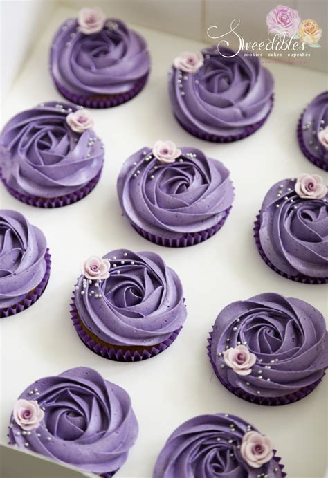 Cupcakes With Purple Frosting And Pink Flowers In A White Box On A Table