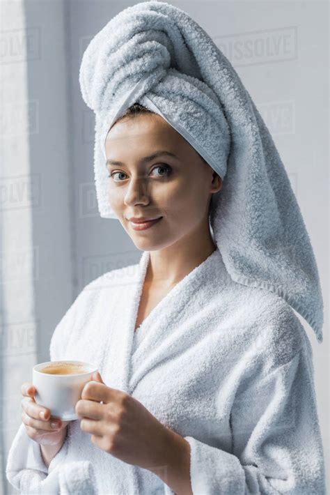 Beautiful Girl In Bathrobe And White Towel On Head Holding Cup Of Coffee And Looking At Camera