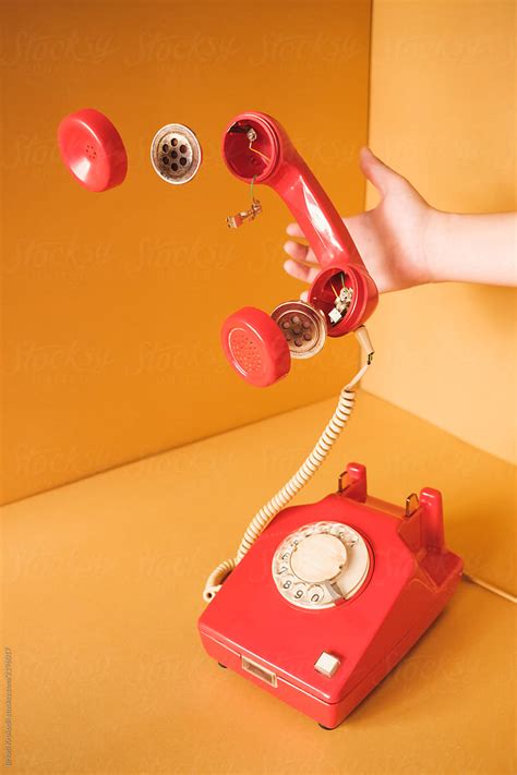 Hand Holding Retro Red Telephone With Parts Floating In The Air By