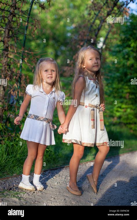 Two Fashion Cute Sisters Go Hand In Hand In The Park Stock Photo Alamy