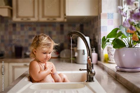 Baby Taking Bath In Kitchen Sink Child Playing With Water And Soap