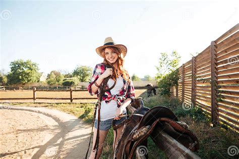Cheerful Smiling Cowgirl Preparing Horse Saddle For A Ride Stock Image