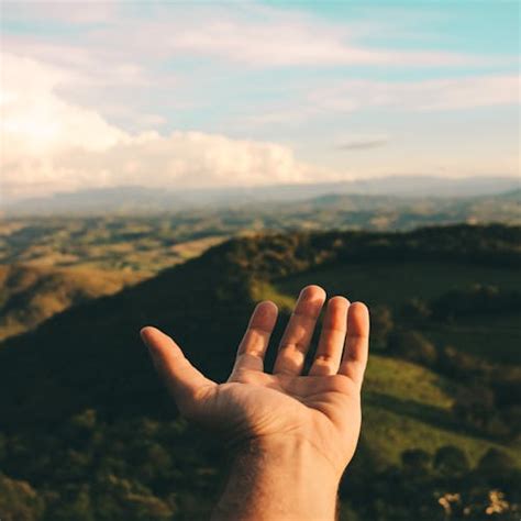 Person Raising Hand Towards Blue Sky During Daytime · Free Stock Photo