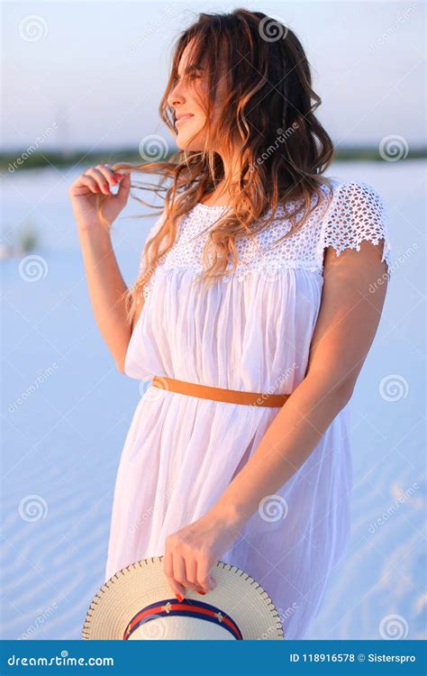 Young Woman Standing On White Sand Wearing Dress And Keeping Ha Stock