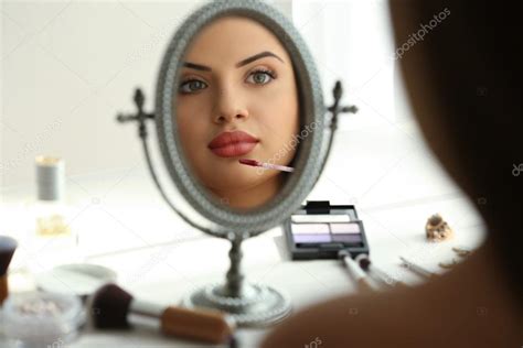 Beautiful Young Woman Looking In Mirror While Applying Makeup — Stock
