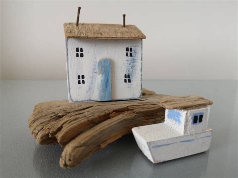 A Small White House Sitting On Top Of A Piece Of Driftwood