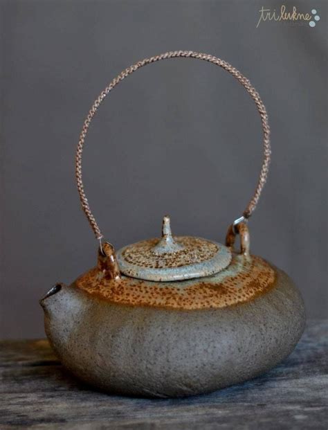 A Teapot With A Chain Hanging From It S Handle On Top Of A Rock