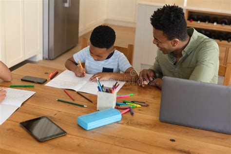 Happy African American Father With Daughter And Son Doing Homework At
