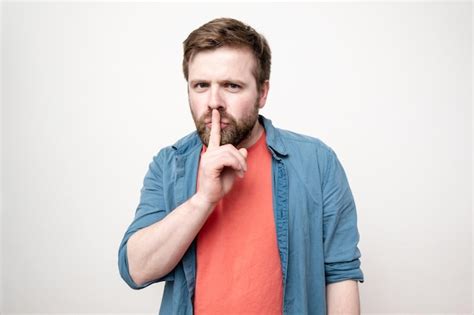 Premium Photo A Bearded Man Puts Index Finger To His Lips Expressing