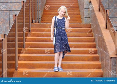 fille blonde à la mode dans l âge de la préadolescence dans une robe se tenant sur un escalier