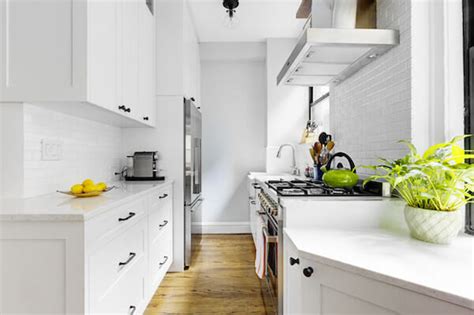 Shaker cabinets offer a simple and traditional design. White Walls and Black Hardware in a Windowed, Pre-War Kitchen