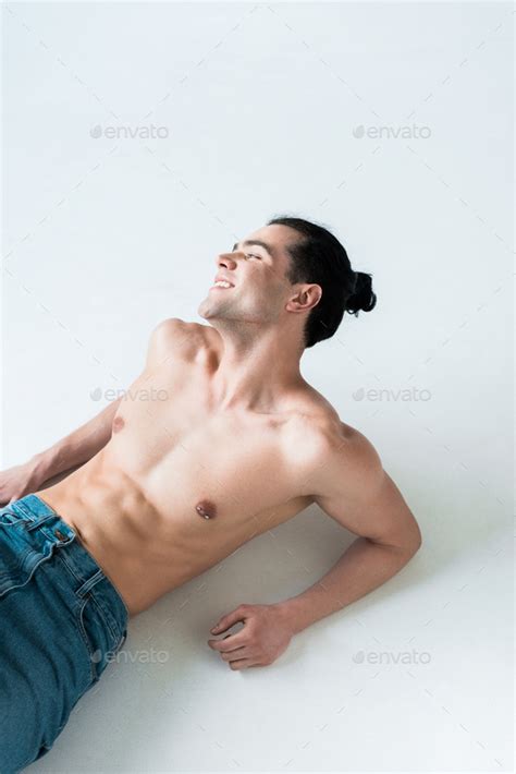 Overhead View Of Cheerful Muscular Man Lying In Blue Jeans On White Stock Photo By LightFieldStudios