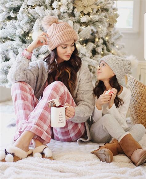 Two Women Sitting In Front Of A Christmas Tree Eating Cookies And Drinking Coffee While Holding Mugs