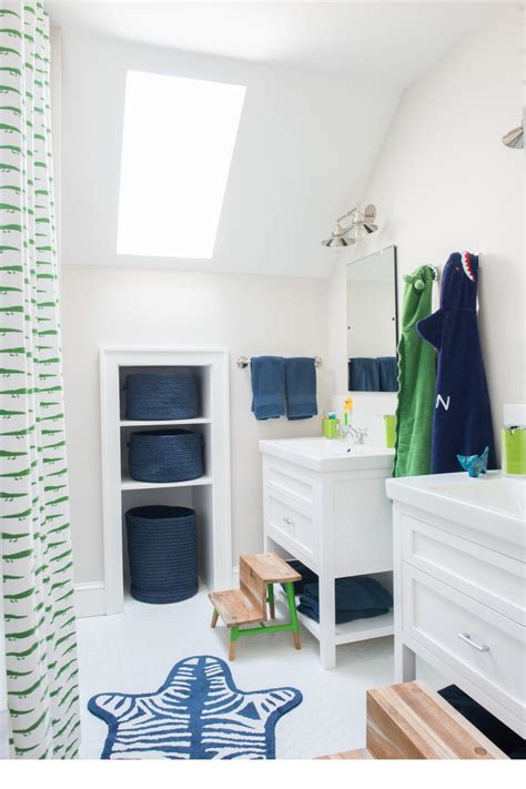 Above the retro pedestal sink is a sunburst shaped mirror made of wood. Navy and Green Details in Kids' Bathroom | HGTV