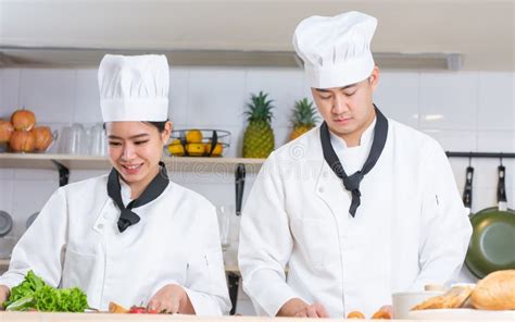 Two Asian Professional Couple Chef Wearing White Uniform Hat Helping Each Other Preparing