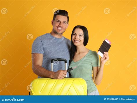 Couple With Suitcase And Tickets In Passports For Summer Trip On Yellow Background Vacation