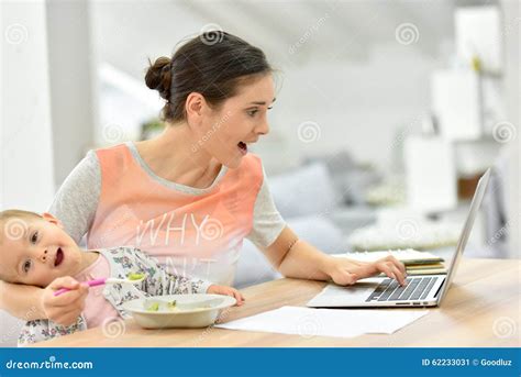 Busy Mother Working On Laptop And Feeding Her Baby Stock Image Image
