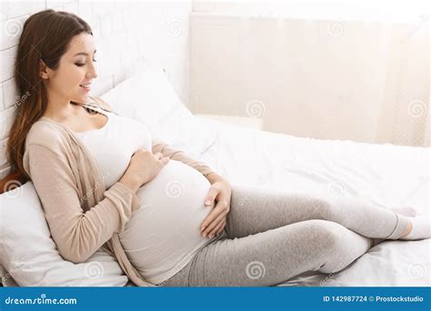 Happy Pregnant Lady Caressing Her Belly Lying In Bed Stock Photo