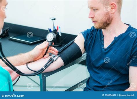 Male Doctor Using Sphygmomanometer With Stethoscope Checking Blood